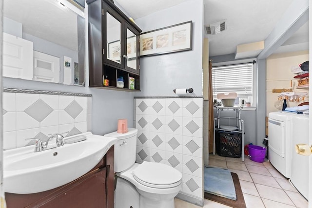 bathroom with separate washer and dryer, tile patterned flooring, toilet, vanity, and tile walls