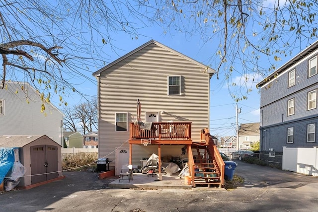 back of house featuring a storage shed, a patio, and a wooden deck