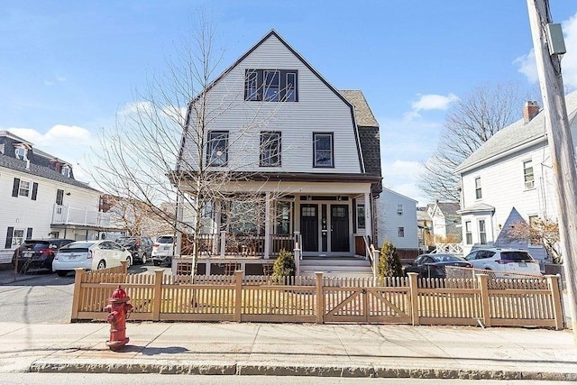 126 Central St Unit 2, Somerville, MA 02145 - view of front facade with covered porch, a gambrel roof, and a fenced front yard