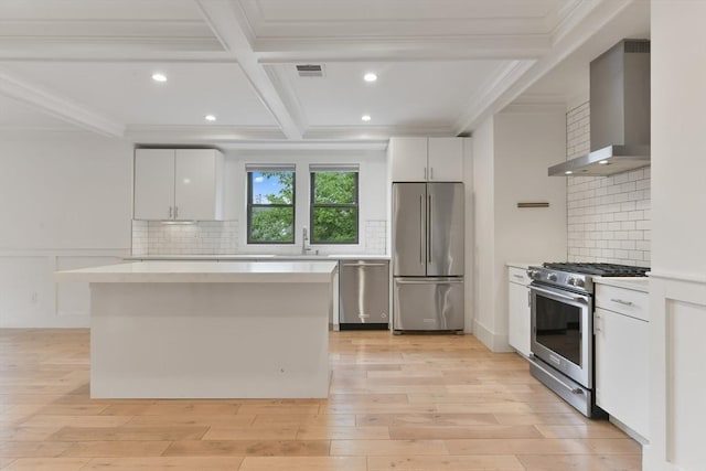 126 Central St Unit 2, Somerville, MA 02145 - kitchen with stainless steel appliances, wall chimney range hood, ornamental molding, light countertops, and white cabinetry
