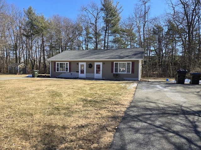 view of front of property featuring a front yard, an outdoor structure, driveway, and a storage unit