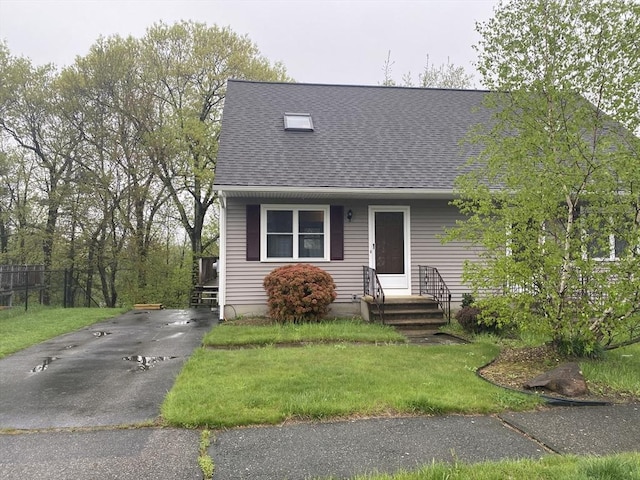view of front of property featuring a shingled roof and a front lawn
