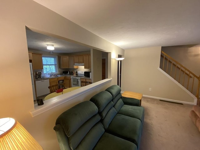 carpeted living room featuring stairs, a sink, and baseboards