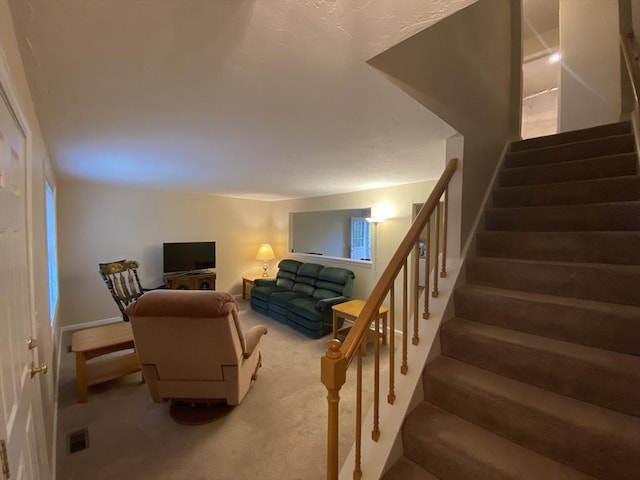 carpeted living room featuring stairs and baseboards