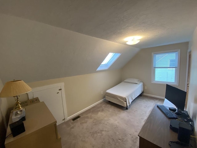 bedroom featuring a skylight, light carpet, vaulted ceiling, baseboards, and a textured ceiling