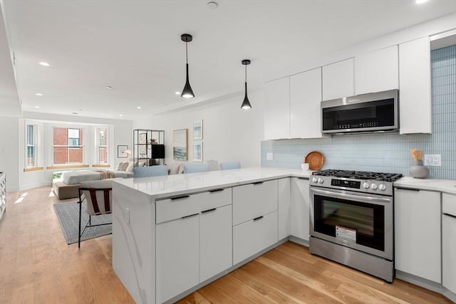 kitchen with kitchen peninsula, white cabinets, and appliances with stainless steel finishes