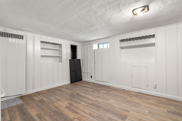 31 Whitman Ave, Melrose, MA 02176 - below grade area featuring built in features, a decorative wall, wood finished floors, baseboards, and a textured ceiling