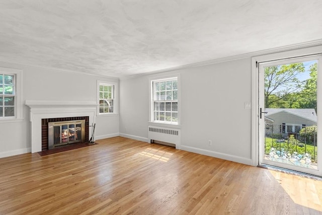 31 Whitman Ave, Melrose, MA 02176 - unfurnished living room with radiator heating unit, light wood-style floors, baseboards, and a brick fireplace