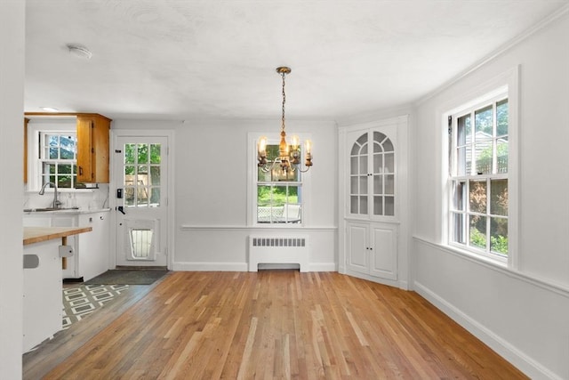 31 Whitman Ave, Melrose, MA 02176 - unfurnished dining area with radiator heating unit, a sink, a chandelier, light wood-style flooring, and plenty of natural light