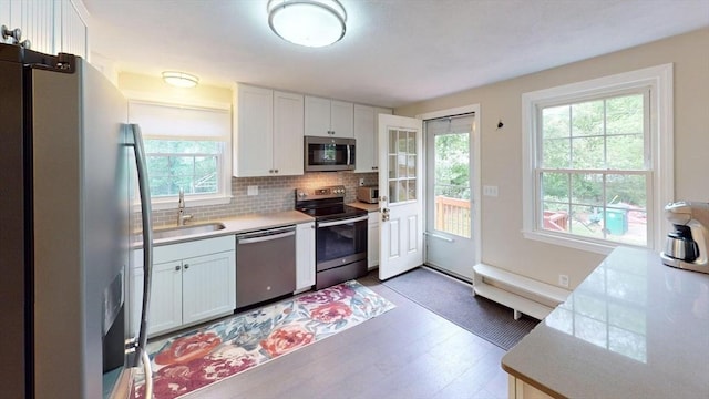 49 Tremont St, Billerica, MA 01821 - kitchen with stainless steel appliances, a sink, backsplash, light countertops, and white cabinetry