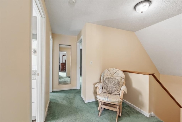 sitting room featuring carpet floors, baseboards, an upstairs landing, vaulted ceiling, and a textured ceiling