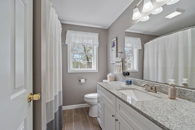 full bath with baseboards, toilet, vanity, and wood finished floors