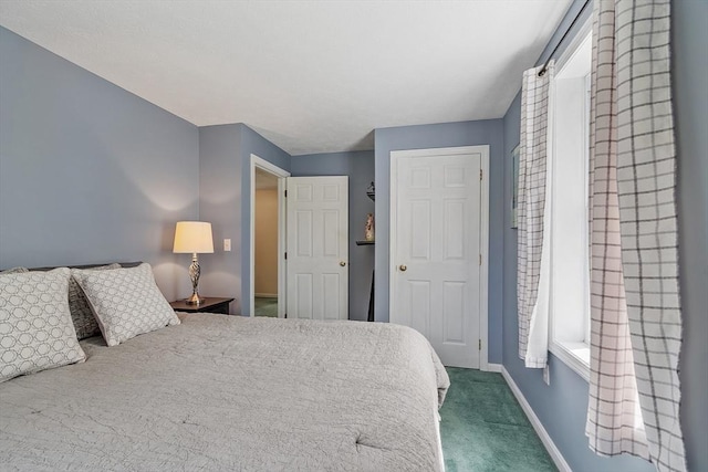 bedroom with dark colored carpet and baseboards