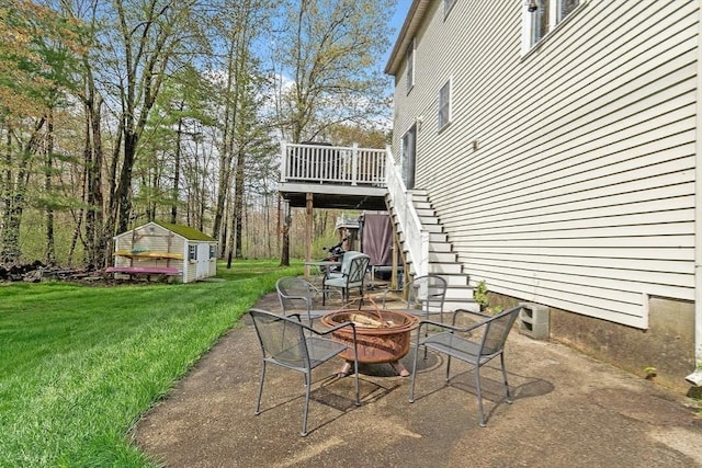 view of patio / terrace featuring an outdoor fire pit, stairway, a wooden deck, and an outbuilding