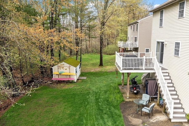 view of green lawn with stairs, an outbuilding, a wooden deck, and a storage unit