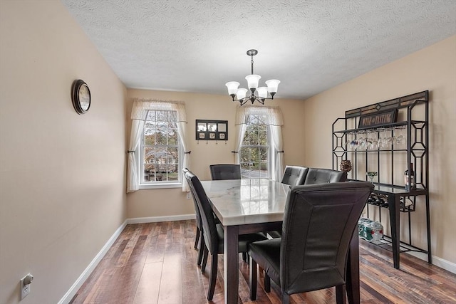 dining space with a chandelier, wood-type flooring, baseboards, and a textured ceiling