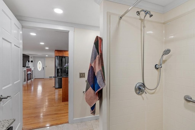 bathroom with hardwood / wood-style floors, a tile shower, and crown molding