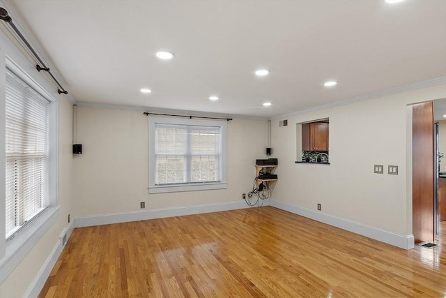 spare room featuring crown molding, a wealth of natural light, and light hardwood / wood-style flooring