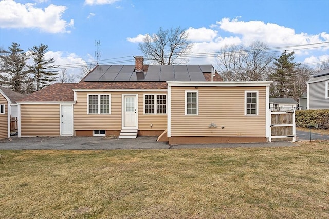 rear view of property with a lawn and solar panels