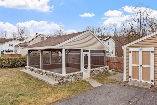 view of outdoor structure with a sunroom and a yard