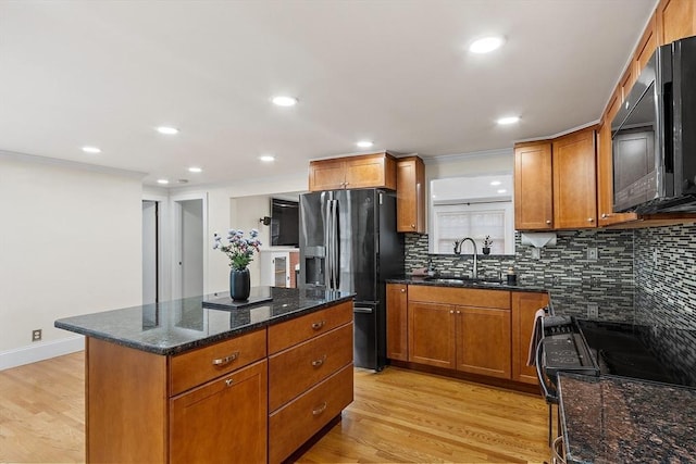 kitchen featuring stainless steel refrigerator with ice dispenser, dark stone counters, sink, a center island, and light hardwood / wood-style floors