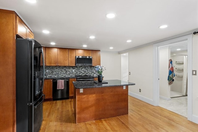 kitchen with backsplash, dark stone counters, black appliances, a center island, and light hardwood / wood-style floors