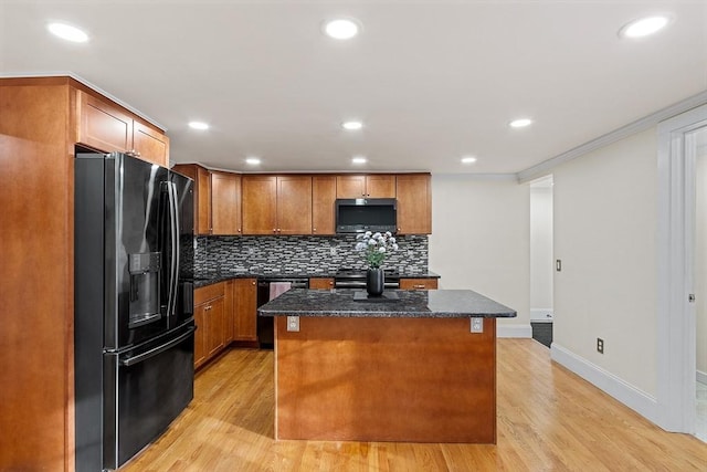 kitchen featuring light wood-type flooring, a center island, ornamental molding, and black appliances