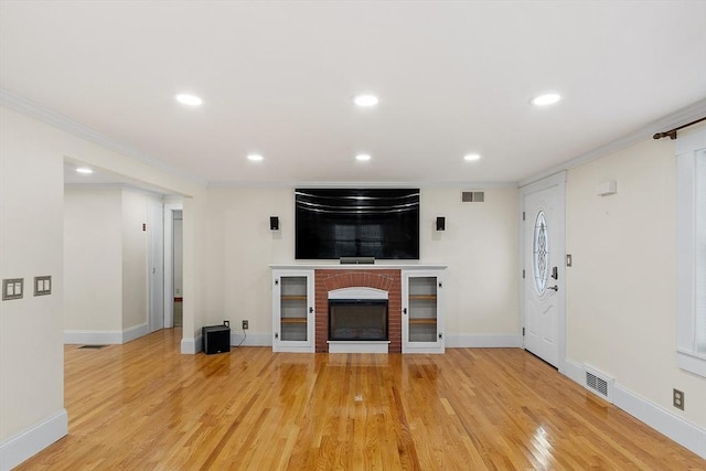 unfurnished living room with a fireplace, light wood-type flooring, and crown molding