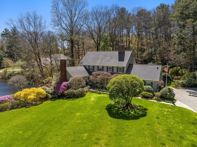 view of front of home featuring a front yard, driveway, and a chimney