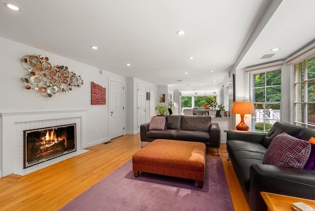 living room featuring a fireplace, light wood finished floors, recessed lighting, visible vents, and baseboards