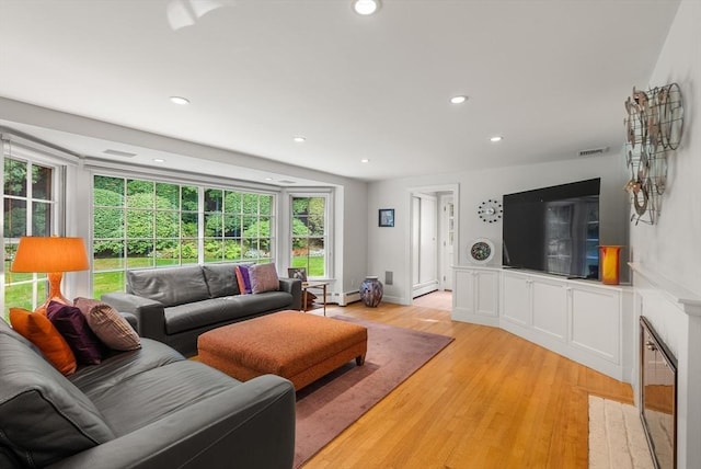 living area featuring visible vents, a high end fireplace, light wood-style flooring, and recessed lighting