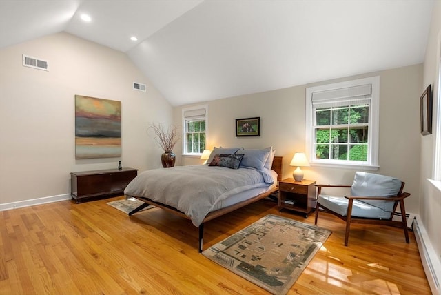 bedroom featuring a baseboard heating unit, visible vents, baseboards, vaulted ceiling, and light wood-type flooring