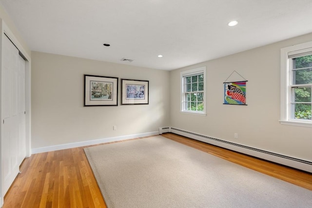 empty room featuring a baseboard radiator, light wood-style flooring, baseboards, and recessed lighting