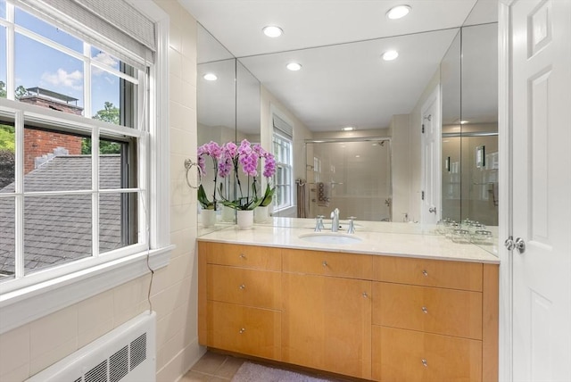 full bathroom with radiator, a shower stall, tile walls, and a wealth of natural light