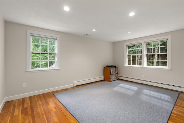 empty room featuring a baseboard radiator, a baseboard heating unit, wood finished floors, and recessed lighting