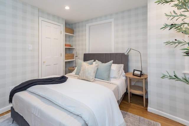 bedroom featuring baseboards, recessed lighting, wood finished floors, and wallpapered walls