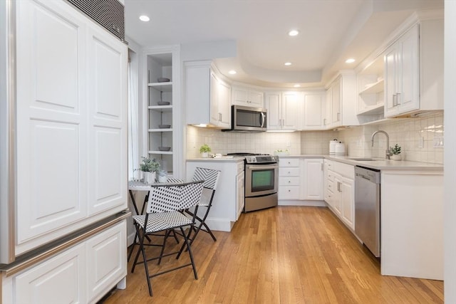 kitchen with open shelves, light countertops, white cabinets, a sink, and stainless steel appliances