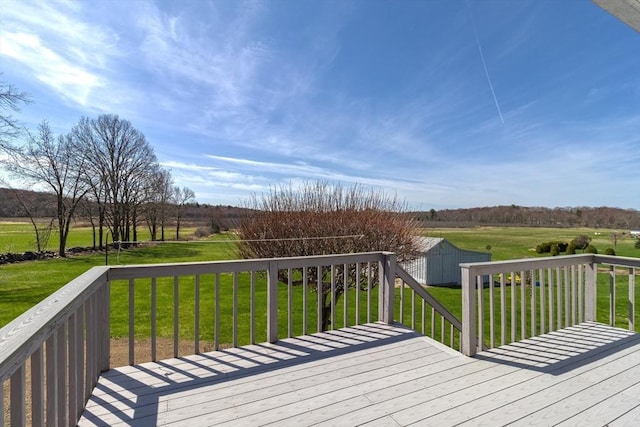 wooden deck with a lawn, an outdoor structure, a rural view, and a shed
