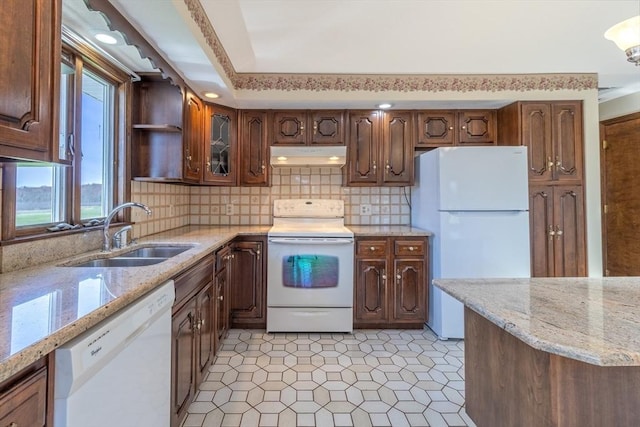 kitchen with a sink, tasteful backsplash, under cabinet range hood, and white appliances