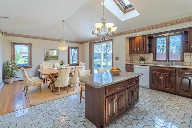 kitchen with a sink, visible vents, an inviting chandelier, dishwasher, and lofted ceiling with skylight