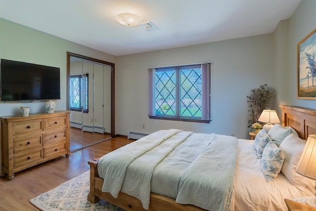 bedroom featuring a baseboard radiator, wood finished floors, visible vents, and a closet