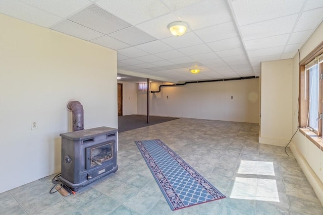 below grade area with a wood stove and a paneled ceiling