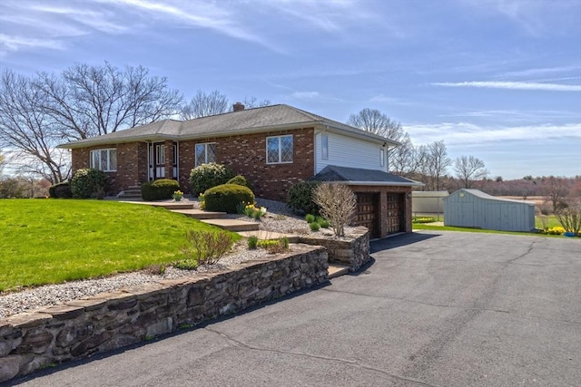 single story home with a garage, brick siding, a front yard, and driveway