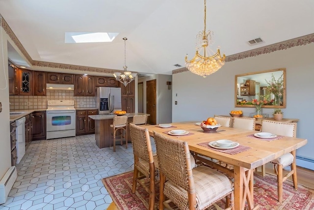 dining space with a chandelier, high vaulted ceiling, visible vents, a skylight, and a baseboard radiator