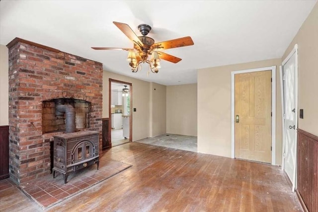 110 Northbridge Rd, Mendon, MA 01756 - unfurnished living room with wood finished floors, a ceiling fan, a wood stove, and a wainscoted wall