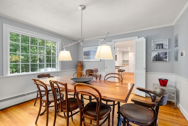 dining area featuring crown molding, light wood-style floors, and a baseboard radiator