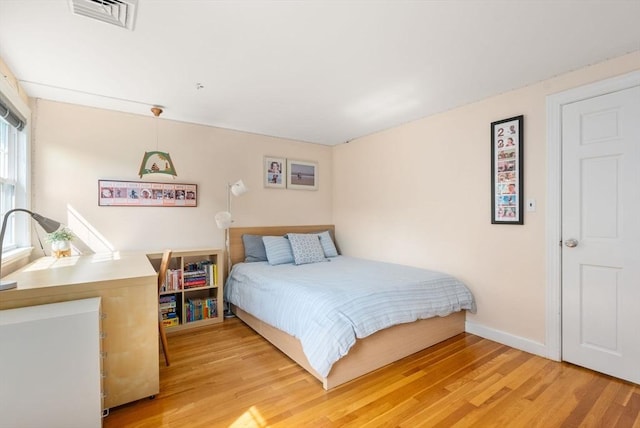 bedroom featuring light wood finished floors, visible vents, and baseboards