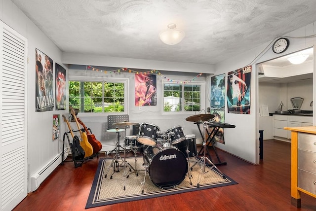 rec room featuring a baseboard heating unit and wood finished floors