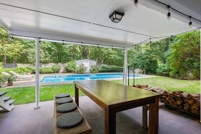 exterior space featuring a storage shed, a patio area, a fenced in pool, and an outbuilding