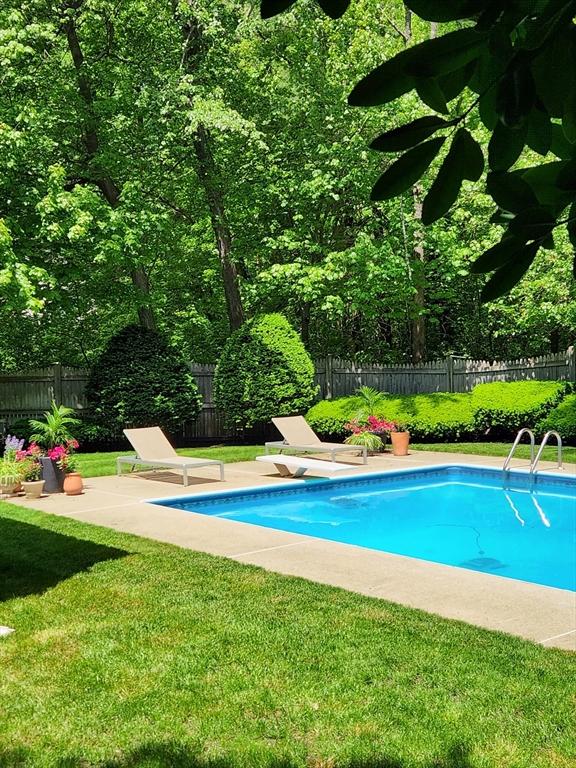 view of pool featuring a fenced backyard, a fenced in pool, a yard, and a diving board